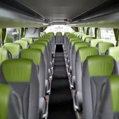 Wnętrze autokaru FlixBus, zielone siedzenia tworzą pusty korytarz. Idealne miejsce na podróż.