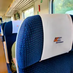 Wnętrze pociągu PKP Intercity. Siedzenia z zagłówkami, na których widnieje logo przewoźnika. Czy bilet PKP z rezerwacją miejsca czy bez – kiedy warto dopłacić?