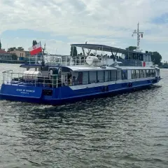 Nadmorski tramwaj wodny "Queen of Szczecin" płynie po wodzie, unosząc polską flagę.