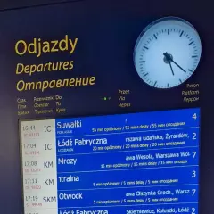 Tablica odjazdów pociągów pokazuje, gdzie sprawdzić opóźnienia pociągu. Widoczne są czasy, kierunki i informacje o opóźnieniach.