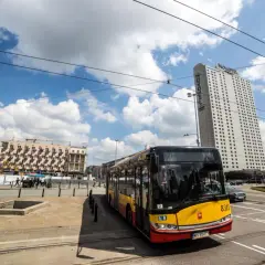 Żółto-czerwony autobus miejski na tle wieżowca Novotel i budynków w Warszawie. Może to być przystanek na trasie autobus warszawa kaliningrad.