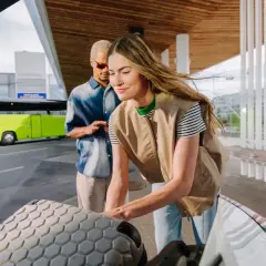 Para dojechać do Złotych Tarasów, wsiądź do zielonego autobusu na terminalu. Para pakuje bagaże do bagażnika.