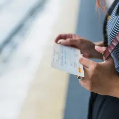 Kobieta trzyma bilet PKP Intercity, zastanawiając się, jak zmienić dane pasażera na bilecie w aplikacji.