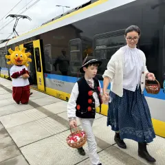 Ludzie w strojach ludowych i Słońce idą na peron, by dowiedzieć się, jak dojechać do Ustronia Górskiego.