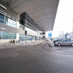 Parking przy Dworcu Centralnym w Warszawie, z widocznym budynkiem Biedronki i samochodami.