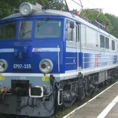 Niebieska lokomotywa EP07-335 PKP Intercity z pociągiem pasażerskim na stacji.