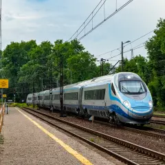 Srebrno-niebieski pociąg Pendolino mija peron. Ile pociągów Pendolino jest w Polsce? Ten jeden jest na torach.