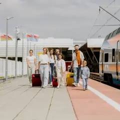 Rodzina z walizkami na peronie, obok pociągu. Planujesz podróż? Sprawdź, jak dojechać do Lublina!