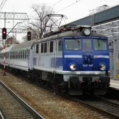 Niebieska lokomotywa PKP Intercity EU07-067 z wagonami na torach kolejowych.