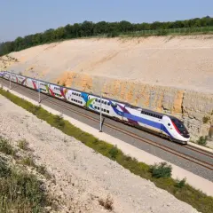 Kolorowy pociąg TGV pędzi po torach, pokazując, jak szybko jedzie pociąg Intercity.