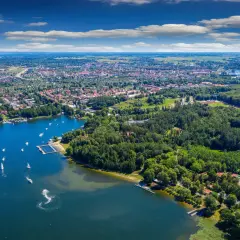 Widok na Giżycko z lotu ptaka, z jeziorem pełnym łodzi i żaglówek. Idealne miejsce na podróż pociągiem do Giżycka.