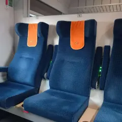 Komfortowe miejsca w pociągu Intercity. Siedzenia są niebieskie, z pomarańczowymi zagłówkami.