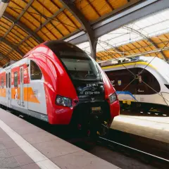 Dwa nowoczesne pociągi stojące na peronie. Czerwony pociąg Polregio i biało-niebieski Impuls, gotowe do podróży. Połączenie kolejowe Wrocław.