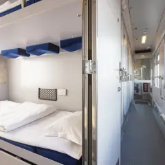 Wnętrze wagonu sypialnego z piętrowymi łóżkami. Zastanawiasz się, ile kosztuje wagon sypialny? To wygodne miejsce na podróż.