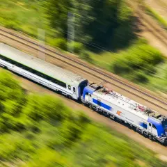 Pociąg PKP Intercity pędzi przez zielone krajobrazy. Chcesz wiedzieć, jak dokupić rezerwację miejsca do kupionego już biletu?