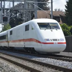 Biały pociąg ICE z czerwonym pasem jedzie po torach. Czy TLK to Intercity? Nie, to niemiecki pociąg dużych prędkości.