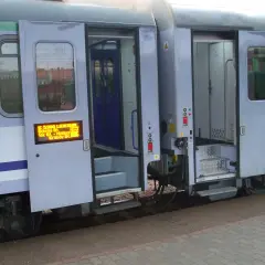 Drzwi wagonu TLK otwarte, widoczne schodki i tablica informacyjna. Jak otworzyć drzwi w TLK? Zwykle przyciskiem lub klamką.