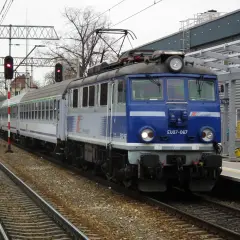 Niebieska lokomotywa PKP Intercity EU07-067 z wagonami na torach kolejowych.