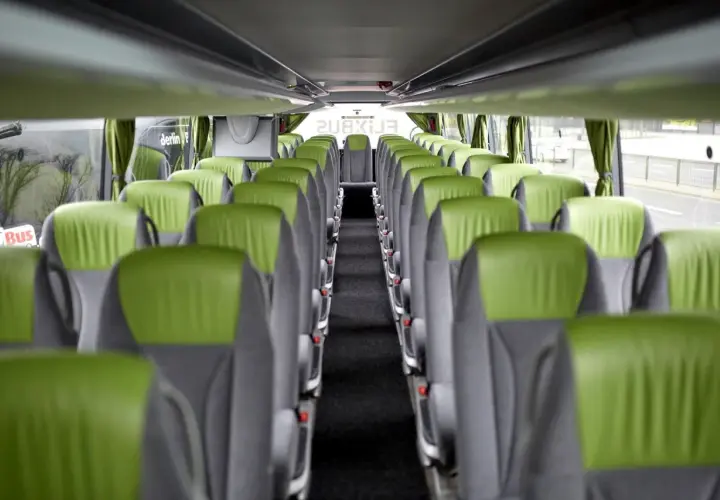 Wnętrze autokaru FlixBus, zielone siedzenia tworzą pusty korytarz. Idealne miejsce na podróż.