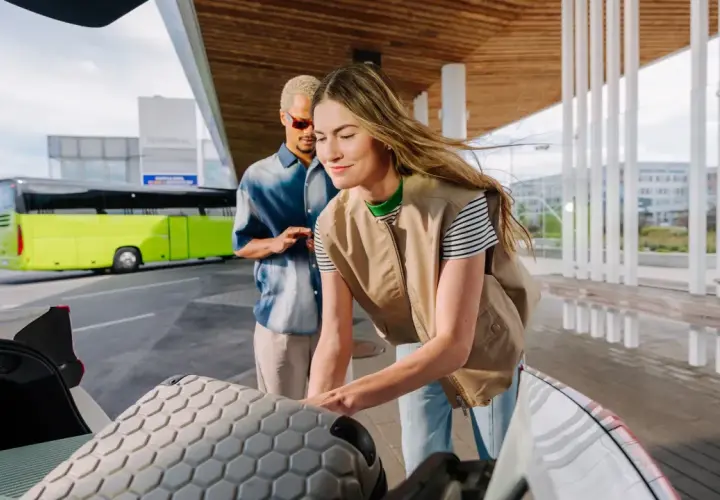 Para dojechać do Złotych Tarasów, wsiądź do zielonego autobusu na terminalu. Para pakuje bagaże do bagażnika.