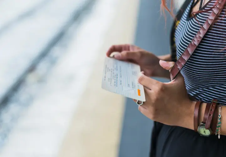Kobieta trzyma bilet PKP Intercity, zastanawiając się, jak zmienić dane pasażera na bilecie w aplikacji.
