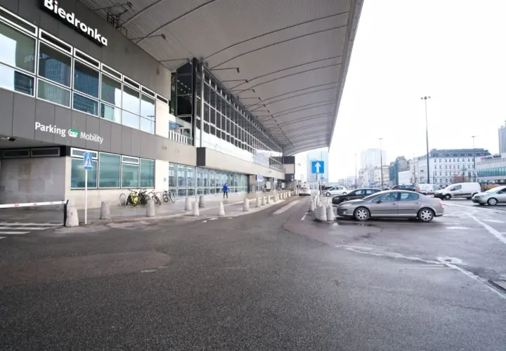 Parking przy Dworcu Centralnym w Warszawie, z widocznym budynkiem Biedronki i samochodami.