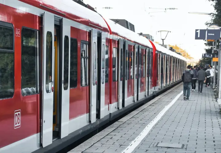 Czerwony pociąg na peronie, ludzie czekają na podróż. Dowiedz się, jak zmienić bilet PKP Intercity, by podróżować bez stresu.