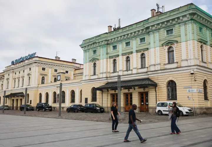 Kraków Główny. Krótki spacer z dworca na rynek, przez plac przed zabytkowym budynkiem, gdzie przechodzą ludzie.