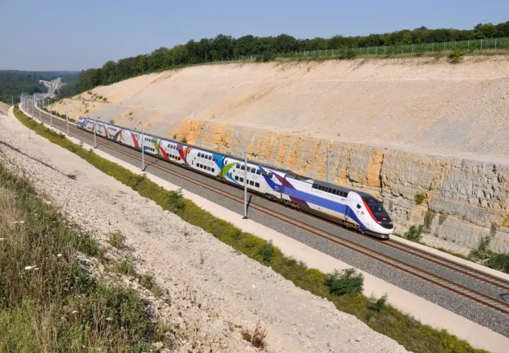 Kolorowy pociąg TGV pędzi po torach, pokazując, jak szybko jedzie pociąg Intercity.