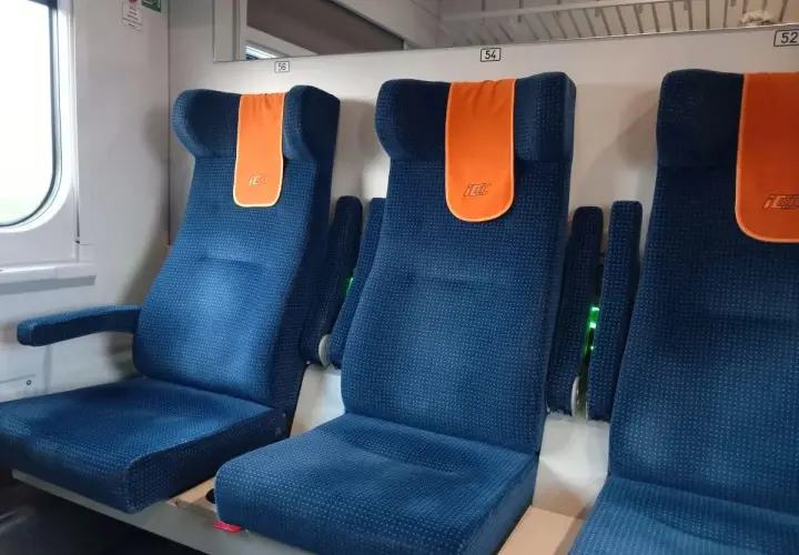 Komfortowe miejsca w pociągu Intercity. Siedzenia są niebieskie, z pomarańczowymi zagłówkami.