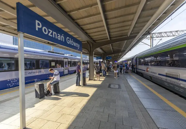 Peron na dworcu Poznań Główny z pociągami i pasażerami.