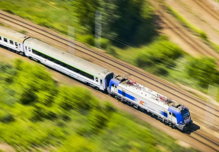 Pociąg PKP Intercity pędzi przez zielone krajobrazy. Chcesz wiedzieć, jak dokupić rezerwację miejsca do kupionego już biletu?