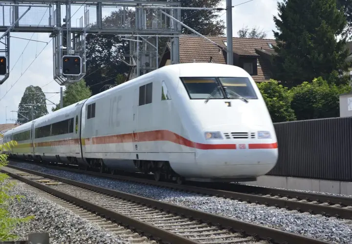Biały pociąg ICE z czerwonym pasem jedzie po torach. Czy TLK to Intercity? Nie, to niemiecki pociąg dużych prędkości.