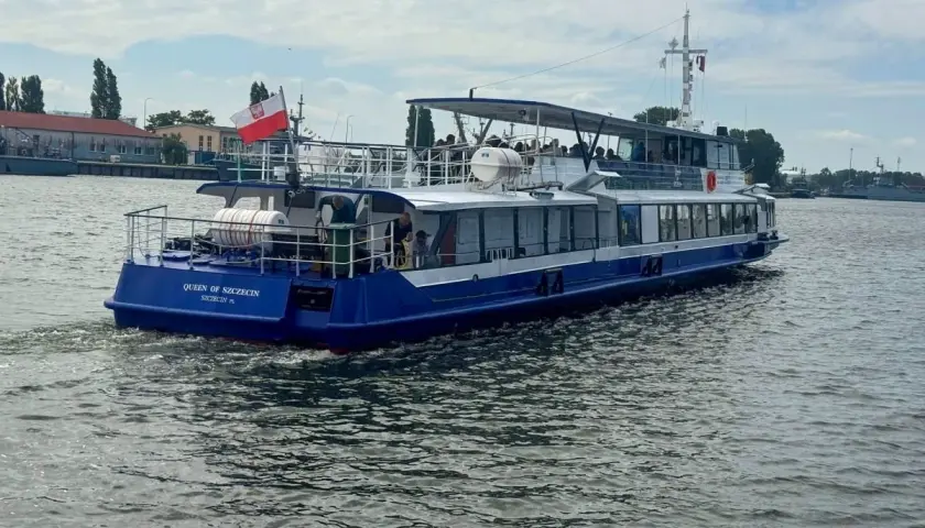Nadmorski tramwaj wodny "Queen of Szczecin" płynie po wodzie, unosząc polską flagę.