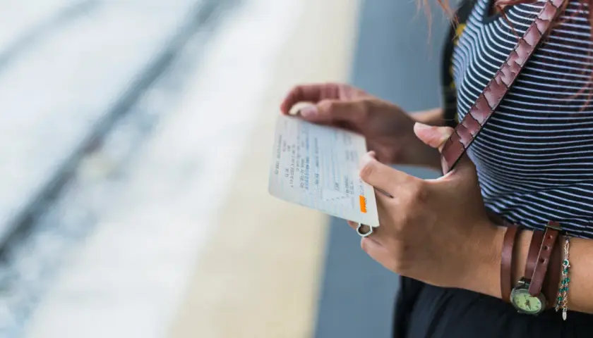 Kobieta trzyma bilet PKP Intercity, zastanawiając się, jak zmienić dane pasażera na bilecie w aplikacji.
