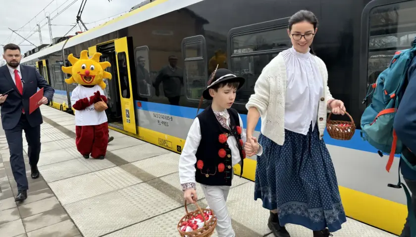 Ludzie w strojach ludowych i Słońce idą na peron, by dowiedzieć się, jak dojechać do Ustronia Górskiego.