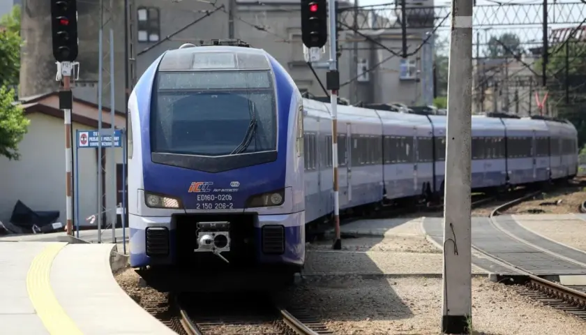 Niebiesko-biały pociąg PKP Intercity ED160-020b na torach, z sygnalizacją świetlną.