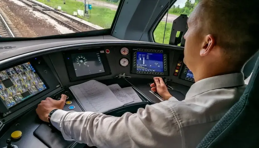 Maszynista PKP w kabinie steruje pociągiem. Zastanawiasz się, ile zarabia kolejarz PKP? To odpowiedzialna praca.