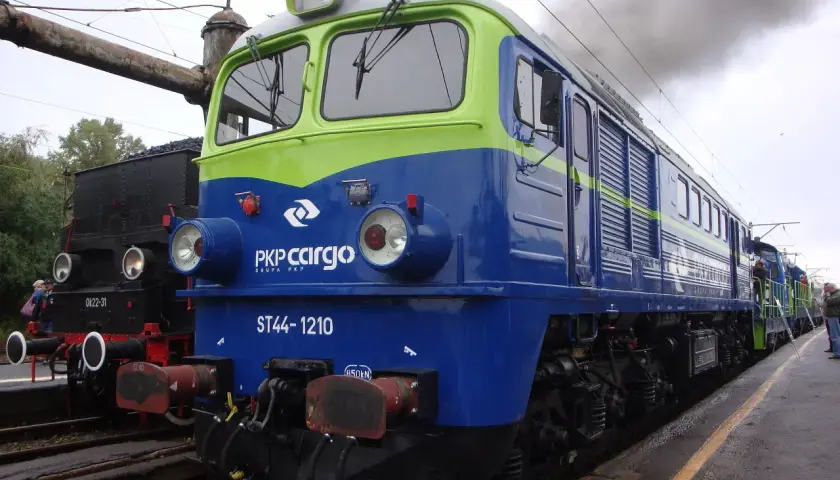 Lokomotywa ST44-1210 PKP Cargo, symbol Solidarności, dymi na tle parowozu.