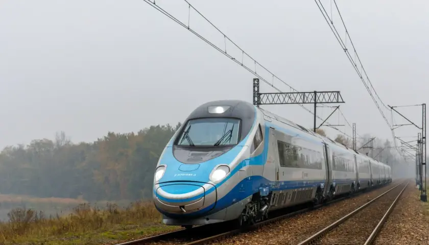 Pendolino pędzi po torach, łącząc Kraków z Warszawą. Pociąg PKP Intercity wjeżdża w mglisty krajobraz.