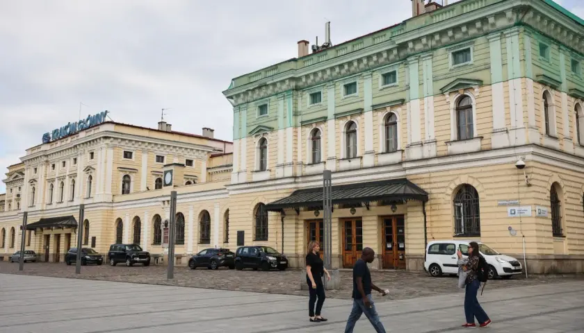 Kraków Główny. Krótki spacer z dworca na rynek, przez plac przed zabytkowym budynkiem, gdzie przechodzą ludzie.