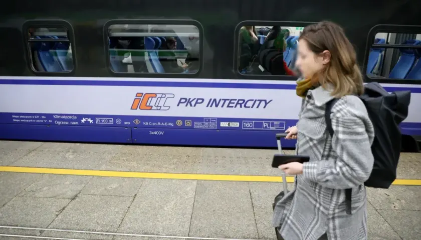 Kobieta z walizką na peronie PKP Intercity, przygotowuje się do podróży mimo podwyżek cen biletów.
