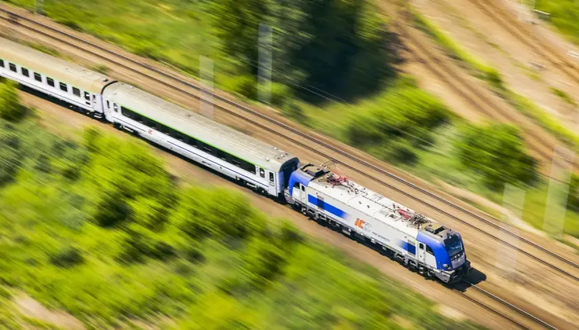 Pociąg PKP Intercity pędzi przez zielone krajobrazy. Chcesz wiedzieć, jak dokupić rezerwację miejsca do kupionego już biletu?