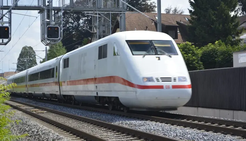 Biały pociąg ICE z czerwonym pasem jedzie po torach. Czy TLK to Intercity? Nie, to niemiecki pociąg dużych prędkości.