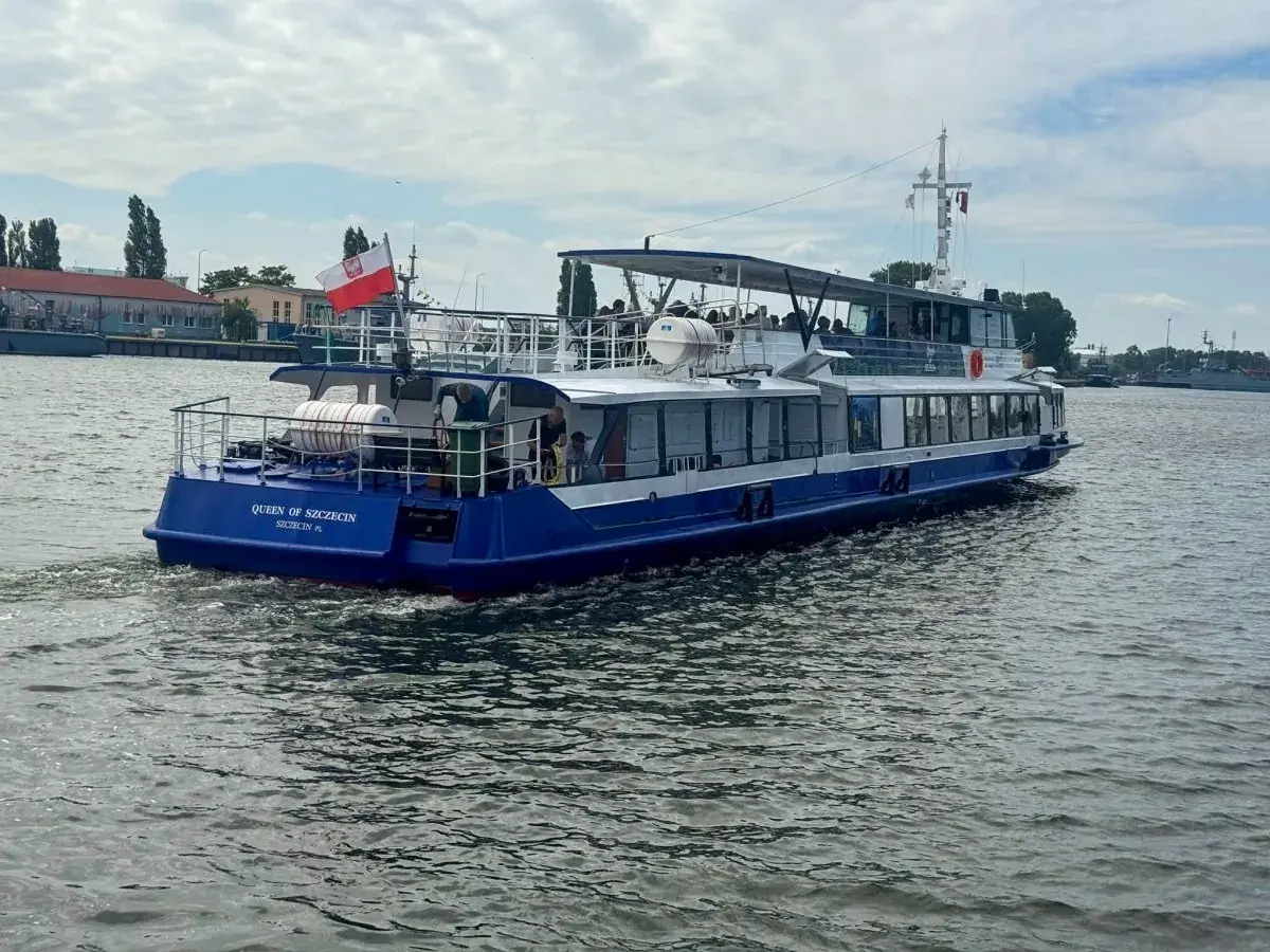 Nadmorski tramwaj wodny "Queen of Szczecin" płynie po wodzie, unosząc polską flagę.