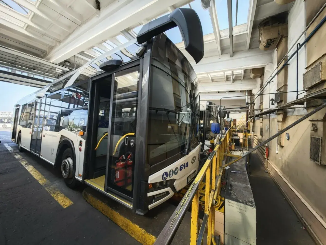 Autobus miejski w zajezdni MZK. Wnętrze hali serwisowej z żółtymi barierkami i wyposażeniem technicznym.