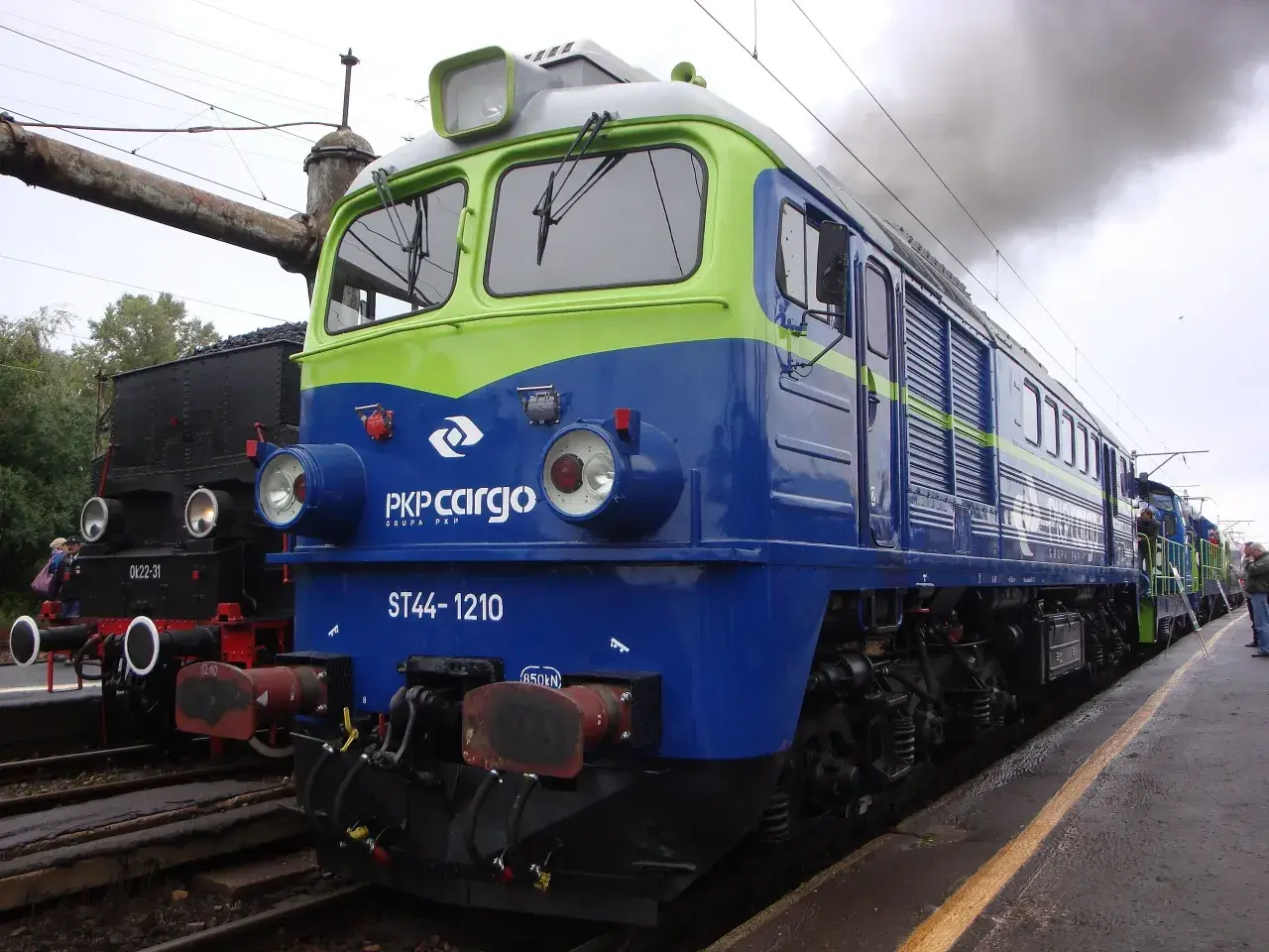 Lokomotywa ST44-1210 PKP Cargo, symbol Solidarności, dymi na tle parowozu.