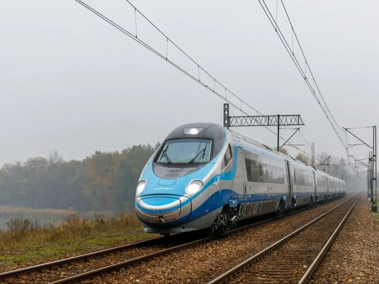 Pendolino pędzi po torach, łącząc Kraków z Warszawą. Pociąg PKP Intercity wjeżdża w mglisty krajobraz.