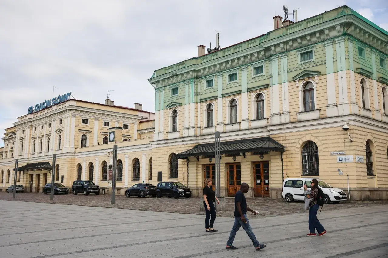 Kraków Główny. Krótki spacer z dworca na rynek, przez plac przed zabytkowym budynkiem, gdzie przechodzą ludzie.
