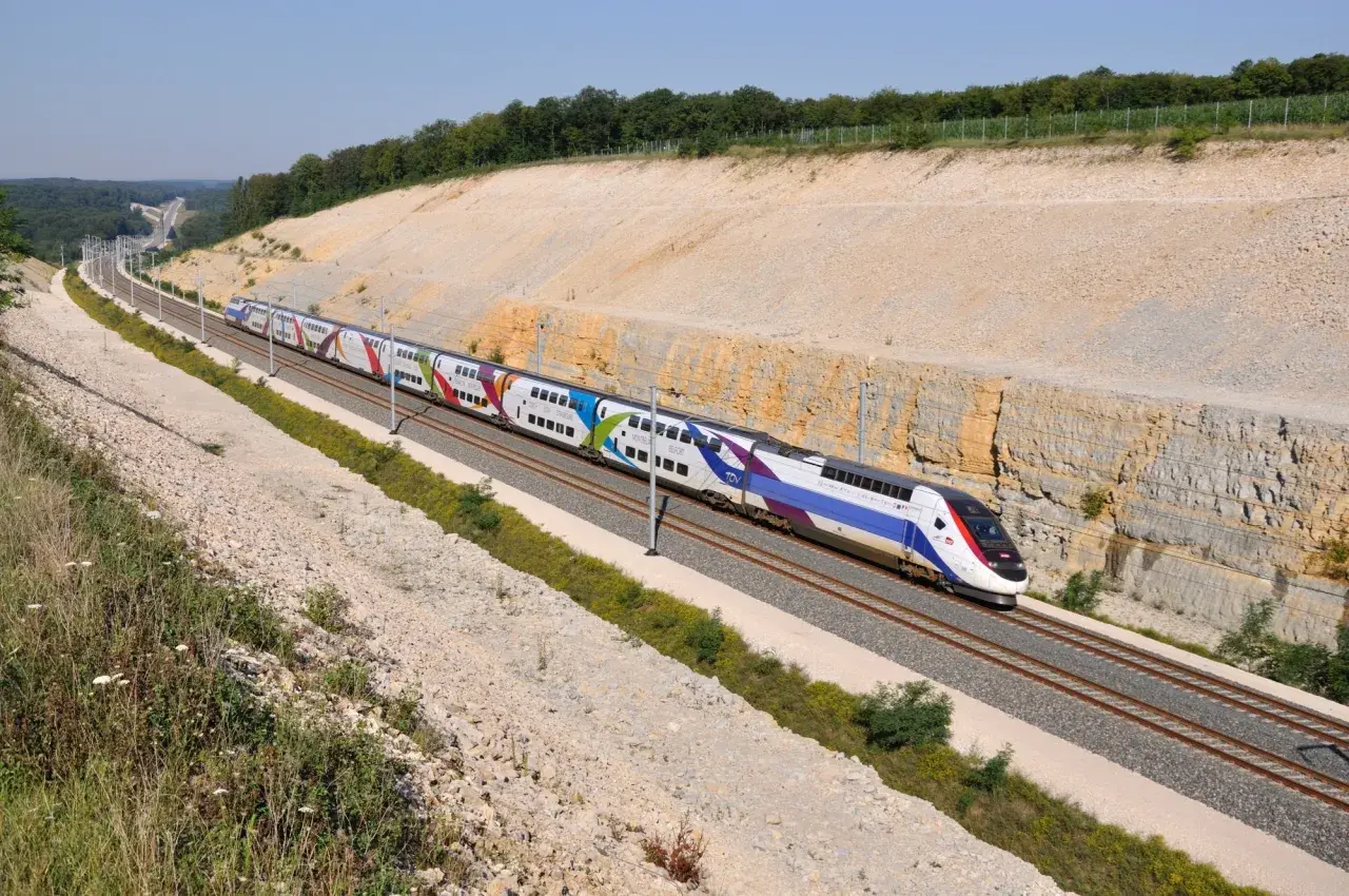 Kolorowy pociąg TGV pędzi po torach, pokazując, jak szybko jedzie pociąg Intercity.